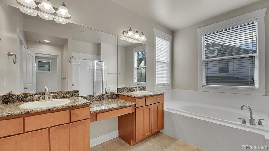 11718 Perry Street Westminster, CO 80031 - Photo 11 of 15 a bathroom with a granite countertop sink a large mirror and a bathtub