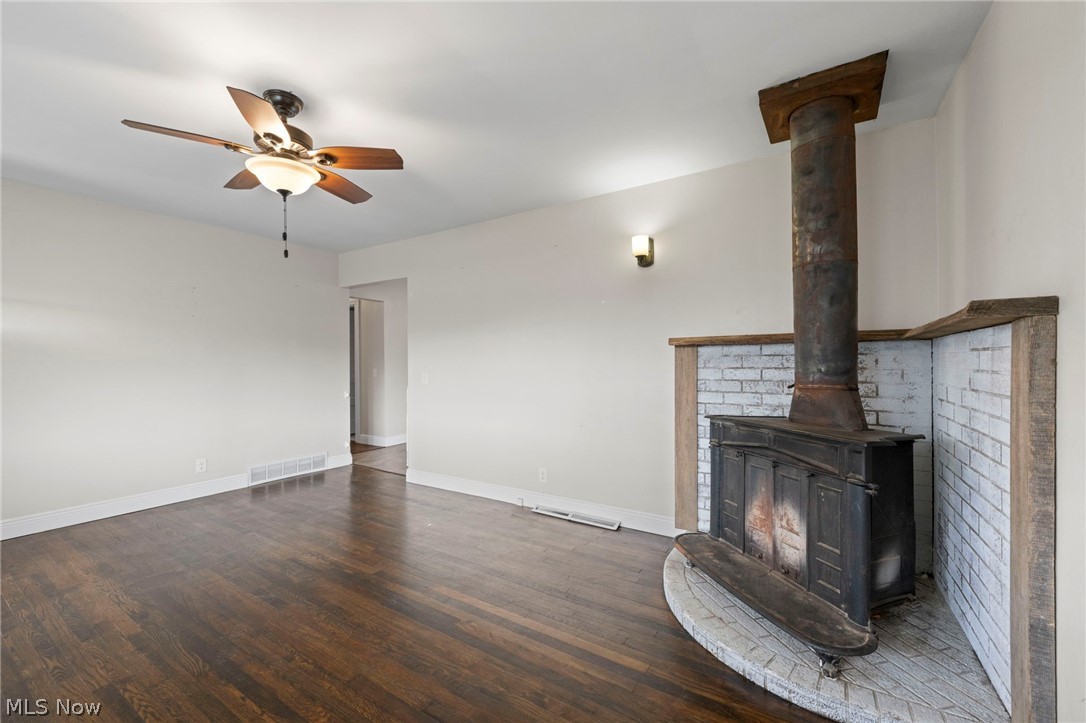 1835 Windham Road Newton Falls, OH 44444 - Photo 6 of 40 Unfurnished living room with dark wood-style flooring, a ceiling fan, and a wood stove