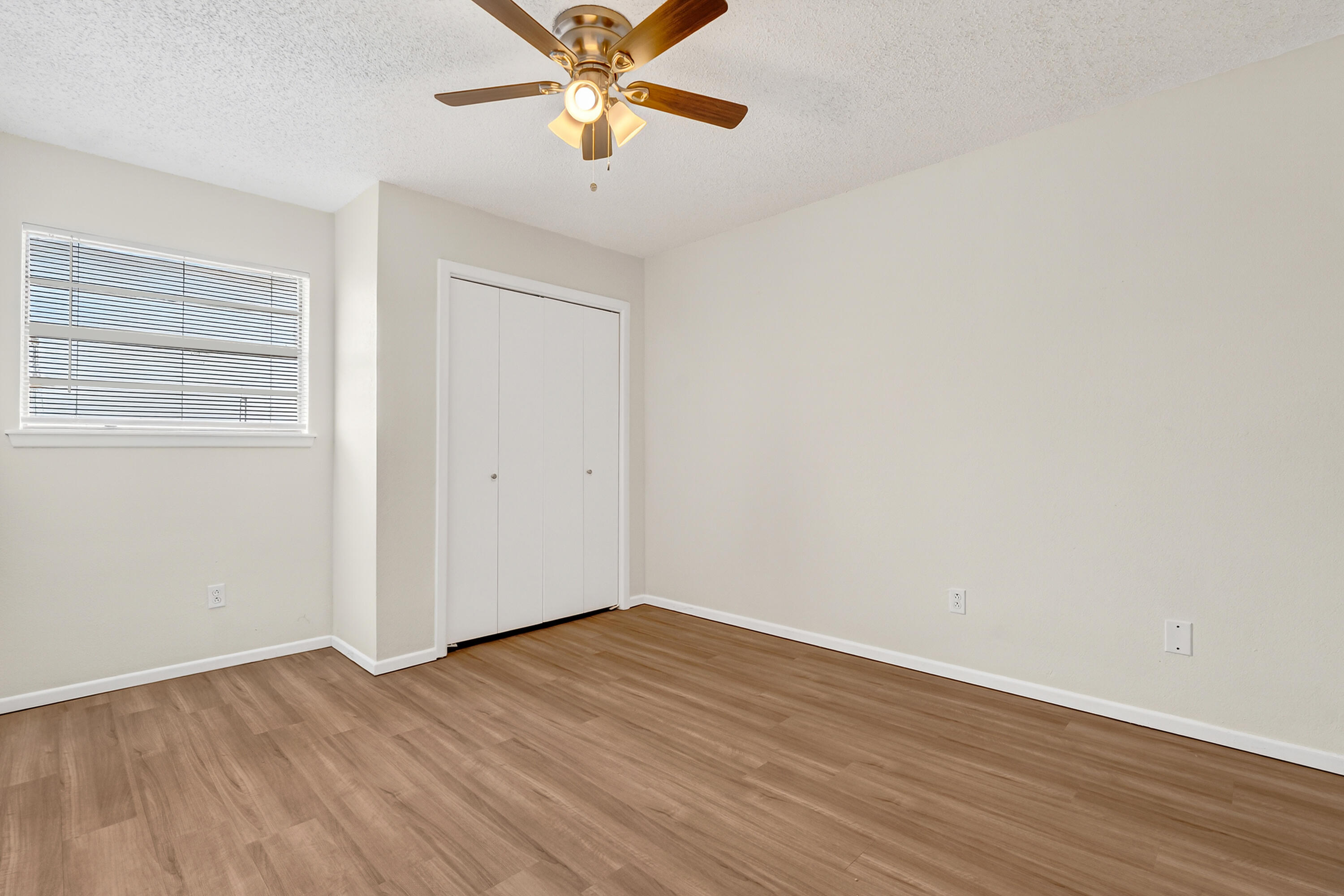 5751 38th Street Lubbock, TX 79407 - Photo 21 of 22 an empty room with wooden floor chandelier fan and windows