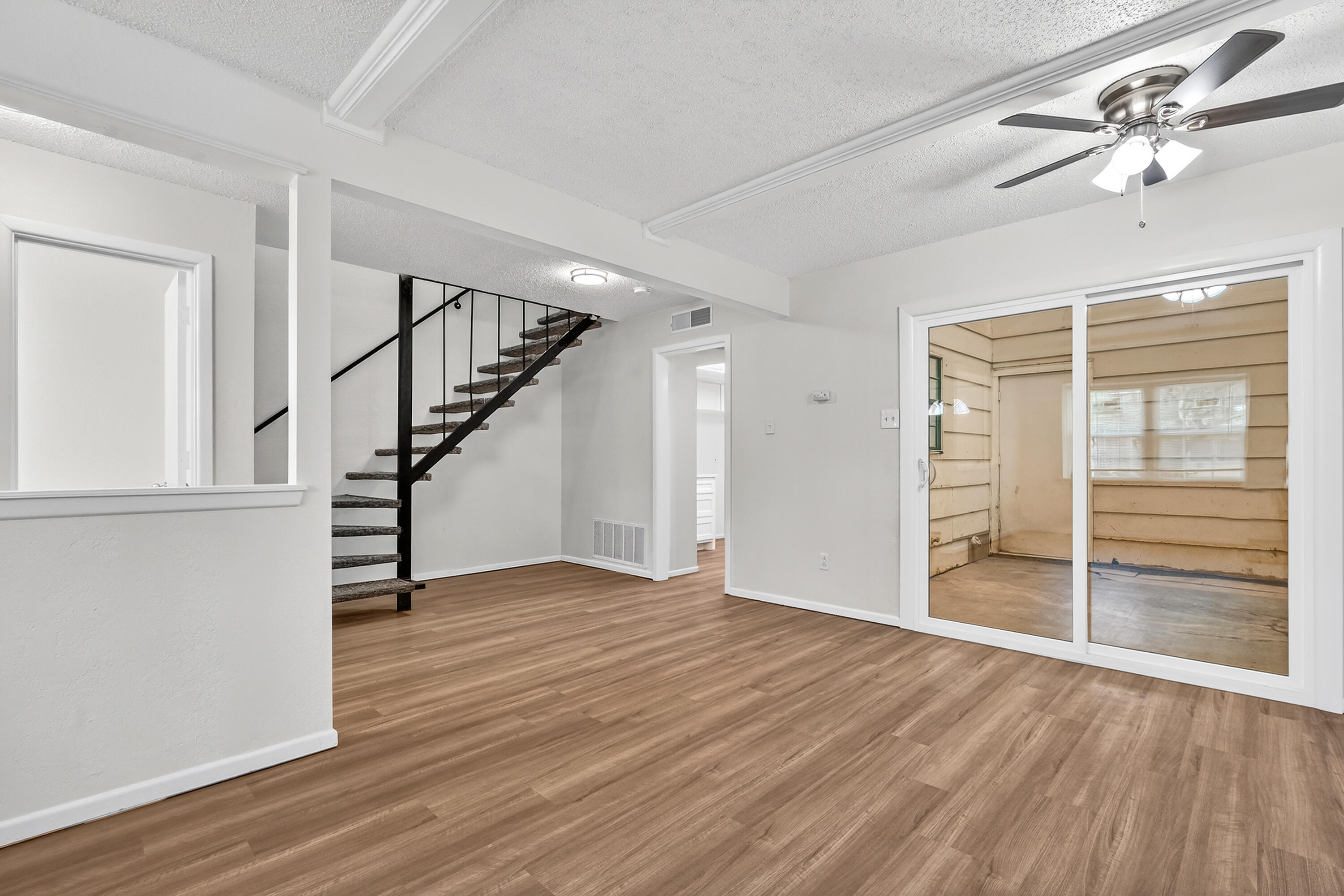 5751 38th Street Lubbock, TX 79407 - Photo 7 of 22 a view of an empty room with wooden floor stairs and a ceiling fan