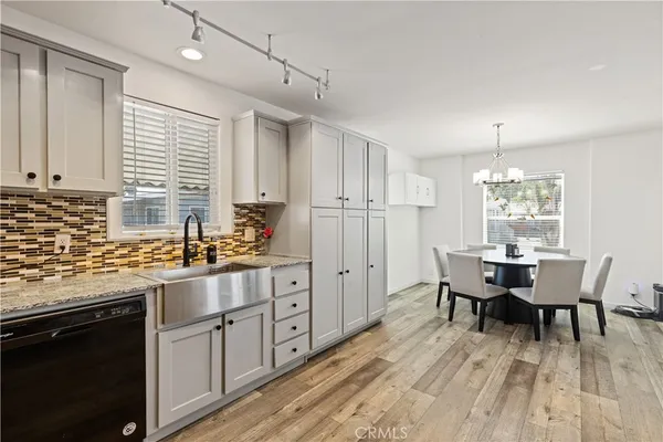 a kitchen with stainless steel appliances granite countertop a stove a sink dishwasher a dining table and chairs with wooden floor