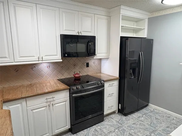 a kitchen with stainless steel appliances granite countertop white cabinets a refrigerator and a stove top oven