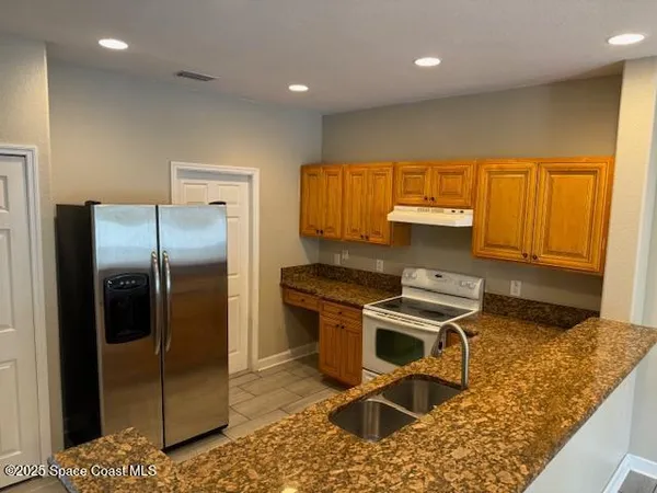 a kitchen with stainless steel appliances granite countertop a refrigerator a stove and a sink