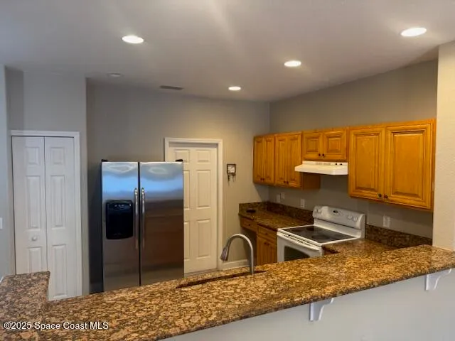 a kitchen with stainless steel appliances granite countertop a refrigerator and a sink