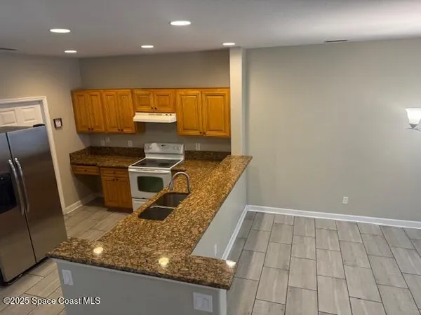 a kitchen with kitchen island granite countertop a sink stove and refrigerator