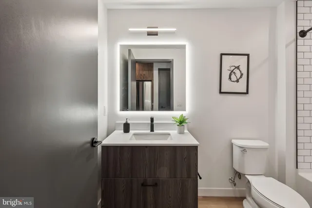 a living room with stainless steel appliances furniture a rug and a kitchen view