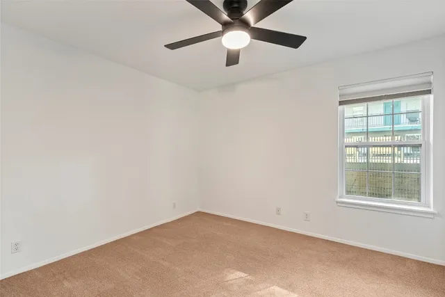 an empty room with a window and a fan
