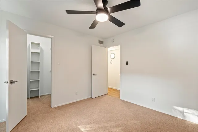 an empty room with closet and a ceiling fan