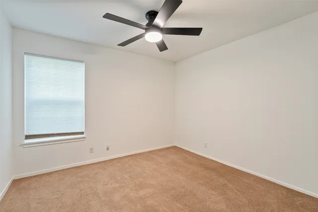an empty room with a window and a fan