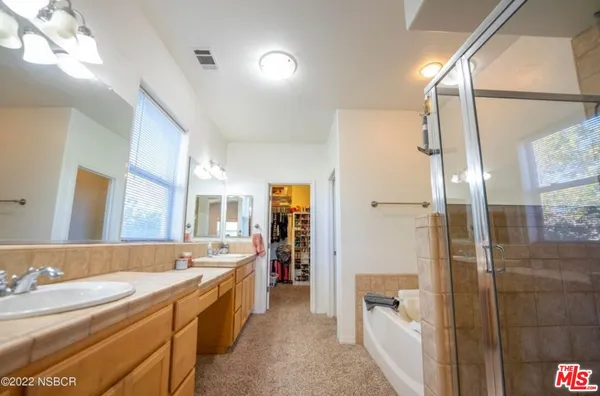 a spacious bathroom with a double vanity sink a large mirror a shower and bathtub