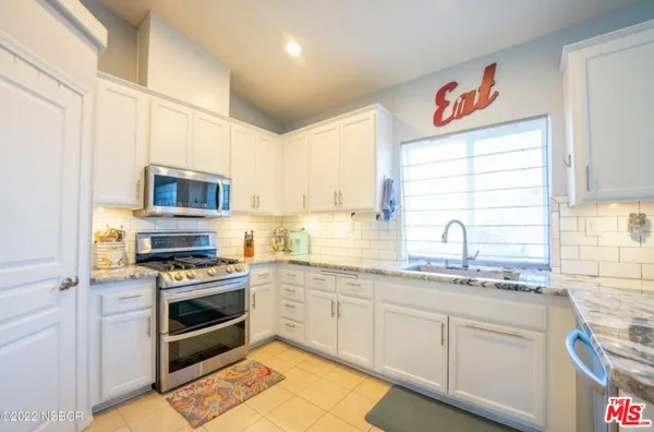 a kitchen with stainless steel appliances granite countertop a stove a sink and a microwave