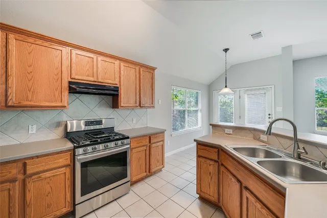 a kitchen with granite countertop a sink stove and cabinets