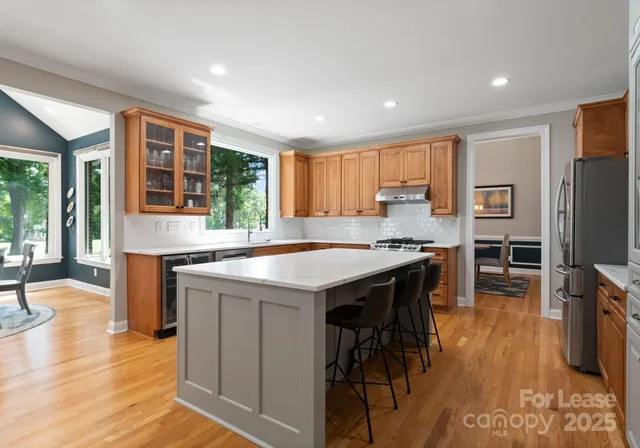 a kitchen with granite countertop a stove a sink a dining table and chairs with wooden floor