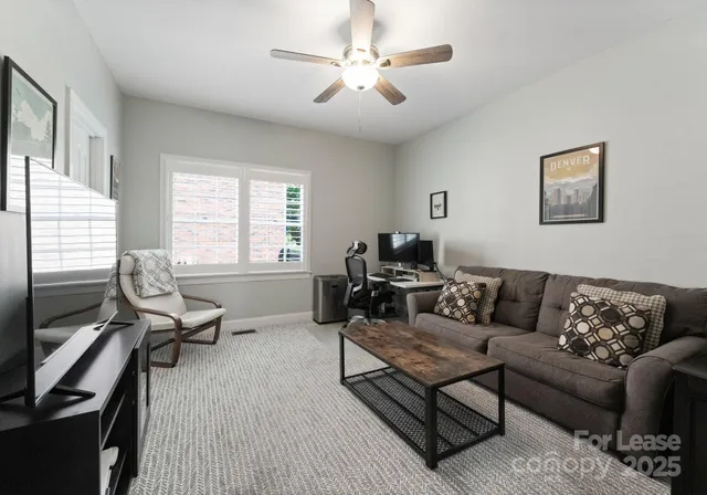 a living room with furniture two window and a ceiling fan