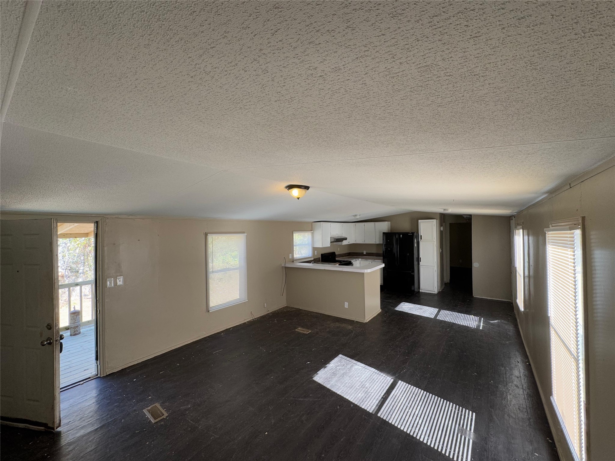 8315 Burleson Manor Road, Unit B Manor, TX 78653 - Photo 8 of 15 Unfurnished living room featuring dark wood-style flooring, lofted ceiling, and a textured ceiling