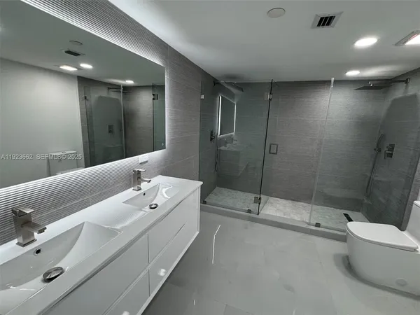 a bathroom with a double vanity sink toilet and shower