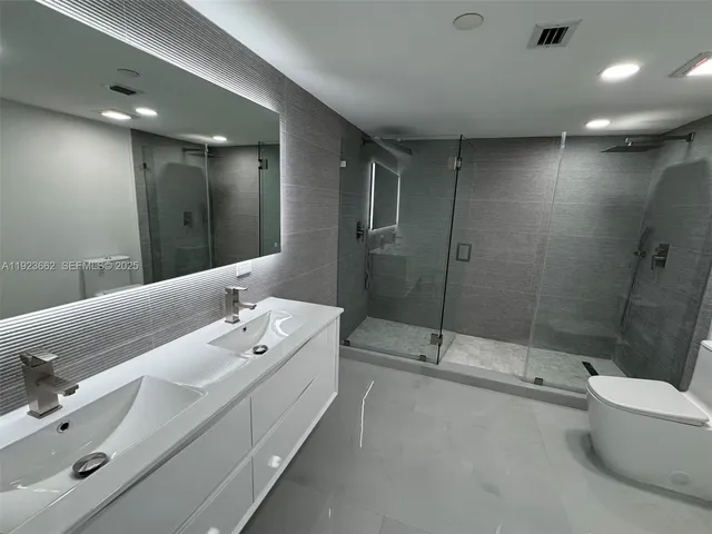 a bathroom with a double vanity sink toilet and shower