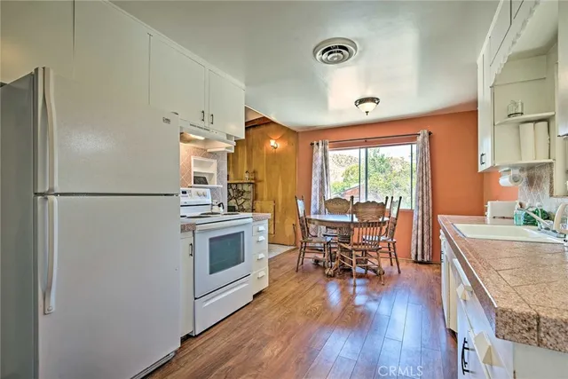 a kitchen with stainless steel appliances granite countertop a refrigerator a sink dishwasher a stove and a dining table with wooden floor