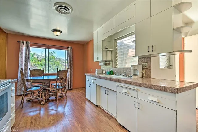 a kitchen with stainless steel appliances granite countertop wooden floors and white cabinets