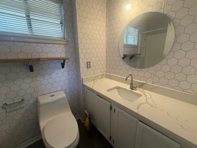 a bathroom with a granite countertop toilet sink and mirror