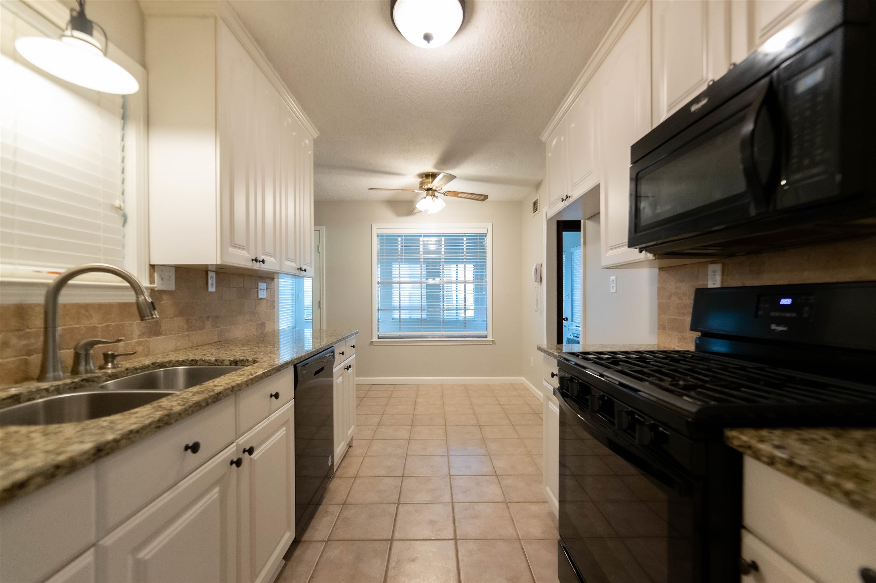 653 Oak Wild Cove Collierville, TN 38017 - Photo 11 of 20 Kitchen featuring light stone counters, sink, white cabinets, black appliances, and backsplash