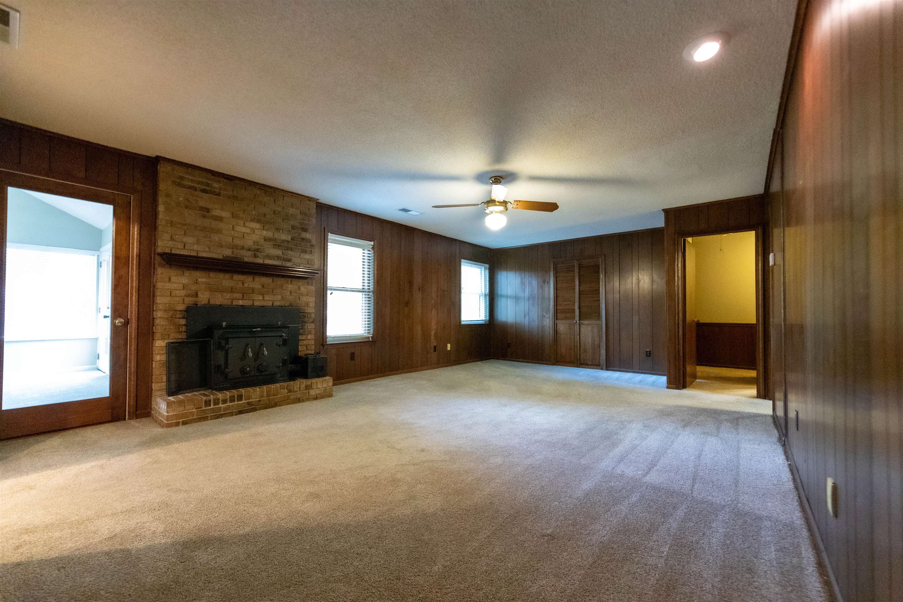 653 Oak Wild Cove Collierville, TN 38017 - Photo 6 of 20 Unfurnished living room featuring light colored carpet, a textured ceiling, wood walls, and a wood stove