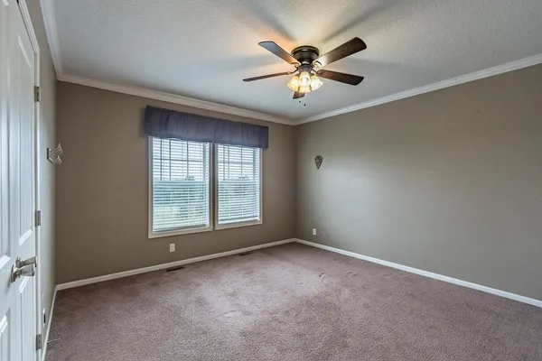 an empty room with chandelier fan and windows