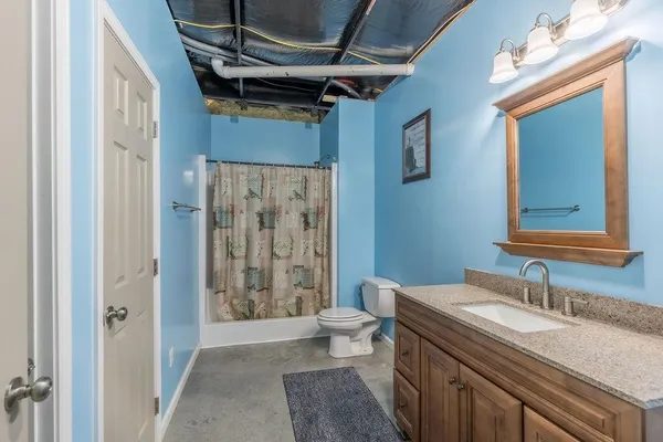 a bathroom with a granite countertop sink a toilet a mirror and shower