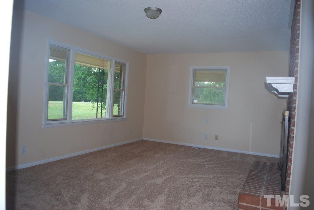 275 Tower Road Henderson, NC 27537 - Photo 4 of 10 Living room with new carpet and brick hearth / wood burning fireplace