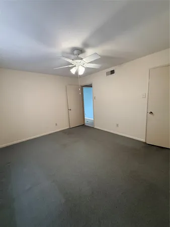 an empty room with a ceiling fan and a window