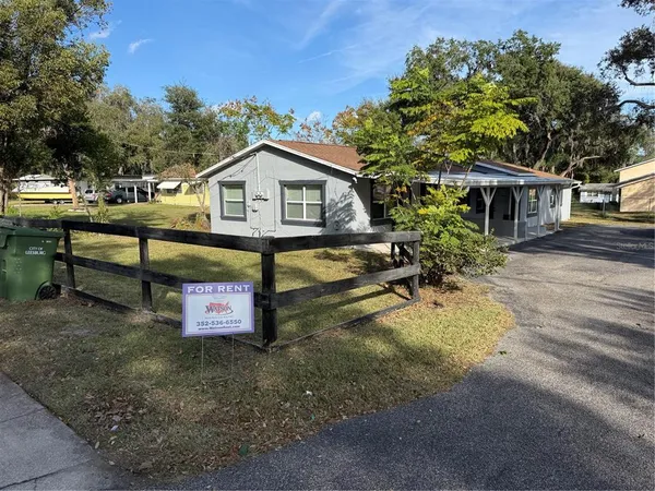 a view of a house with wooden fence and a tree
