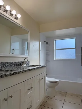 a bathroom with a granite countertop sink a toilet and a mirror