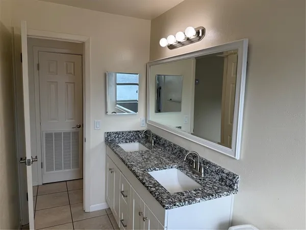 a bathroom with a granite countertop sink and a mirror