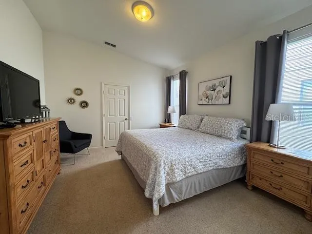 a spacious bedroom with a bed and a flat screen tv