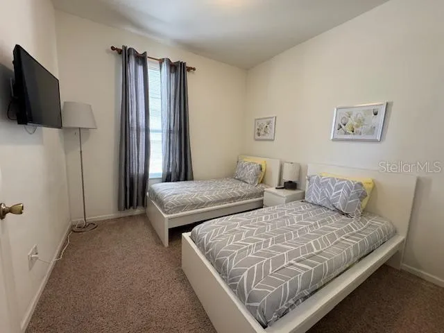 a bedroom with two beds and flat screen tv
