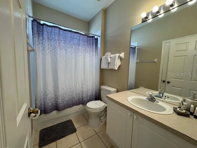 a bathroom with a sink a toilet a mirror and shower curtain
