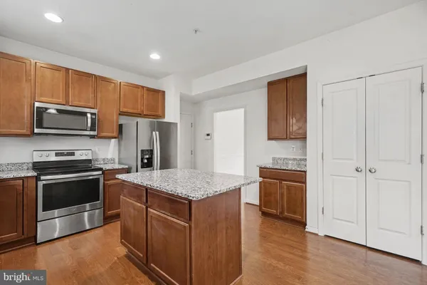 a kitchen with stainless steel appliances granite countertop a refrigerator a sink dishwasher a stove with wooden cabinets and a refrigerator