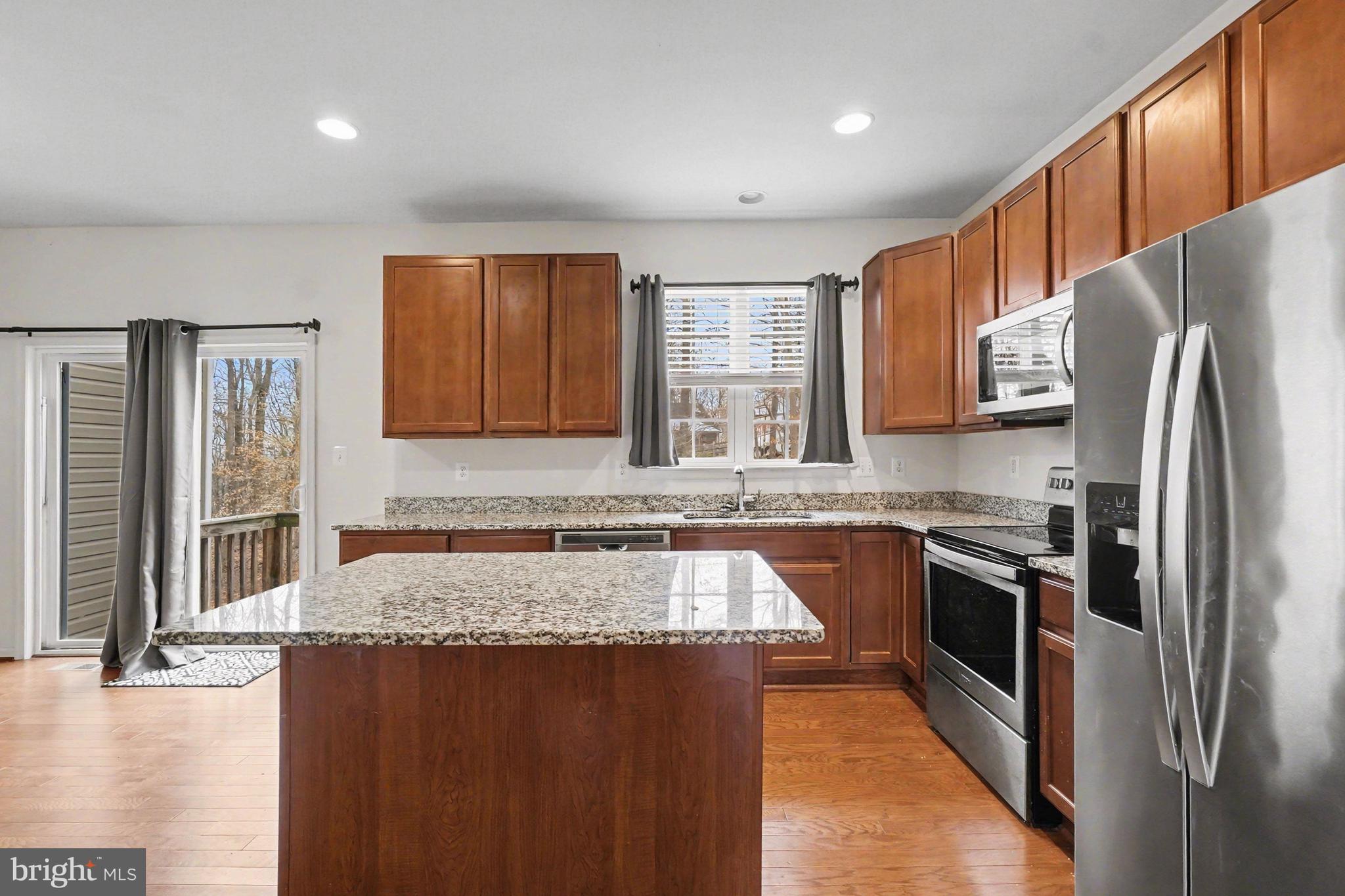 35 Sparrows Way Elkton, MD 21921 - Photo 14 of 36 a kitchen with stainless steel appliances granite countertop a refrigerator a sink dishwasher a stove top oven and a dining table with wooden floor