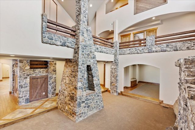 246 Woods Creek Road Morgan, UT 84050 - Photo 21 of 69 Two-story living area featuring a stone fireplace, stone accent walls, vaulted ceilings, and an upper-level balcony with wood railings
