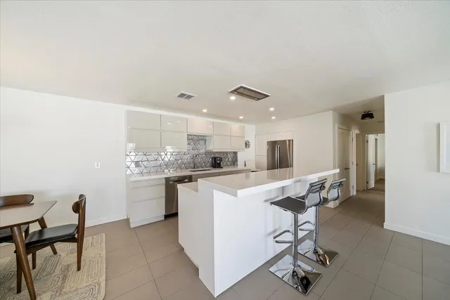 a kitchen with kitchen island a stove a table and chairs in it