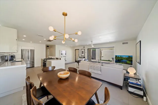 a view of a dining room and livingroom with furniture wooden floor a rug a fireplace and a chandelier