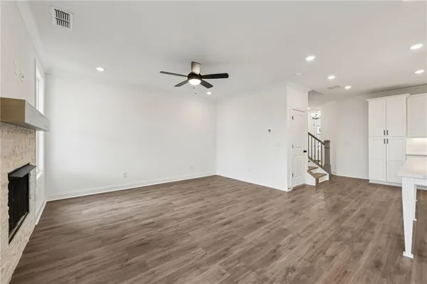 a view of an empty room with wooden floor and a fireplace