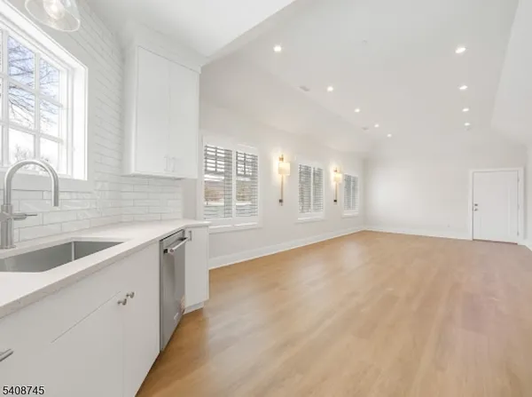 a view of a kitchen with granite countertop white cabinets and wooden floor