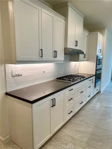 a kitchen with granite countertop white cabinets and a stove