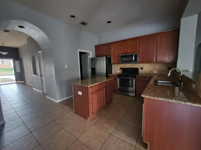 a kitchen with stainless steel appliances granite countertop a stove a sink and a refrigerator