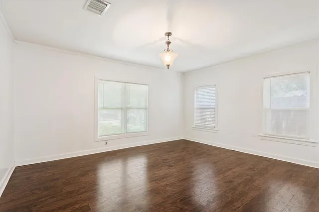 an empty room with wooden floor chandelier fan and windows