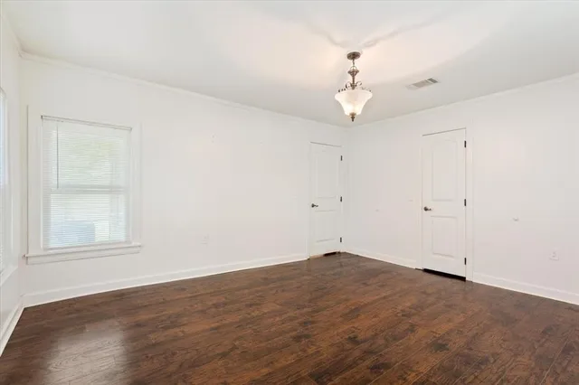 an empty room with wooden floor ceiling fan and window