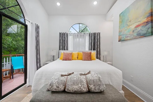 a bedroom with a bed a painting on the wall and a large window