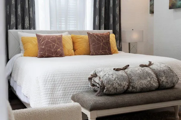 a large white bed sitting in a bedroom next to a window