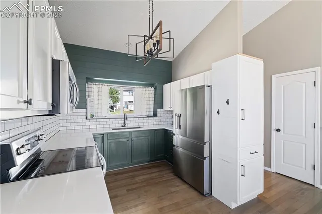 a kitchen with stainless steel appliances granite countertop a refrigerator a sink dishwasher a stove and a dining table with wooden floor